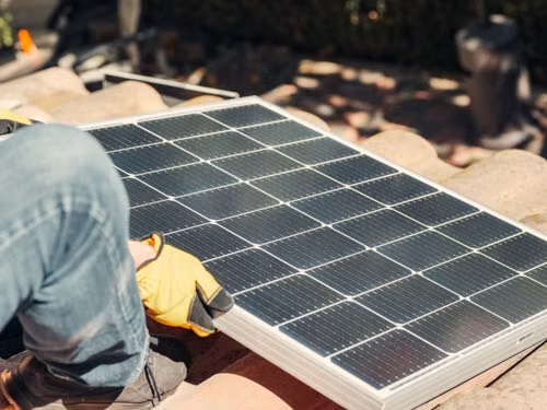 a roofing contractor installing a solar panel in an Arizona home.
