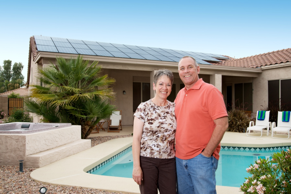 Homeowners standing outside a Phoenix home with rooftop solar panels installed by a woman-owned solar company in Arizona