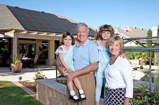  Family standing near a Phoenix home with solar panels showing values-driven solar and roofing project care
